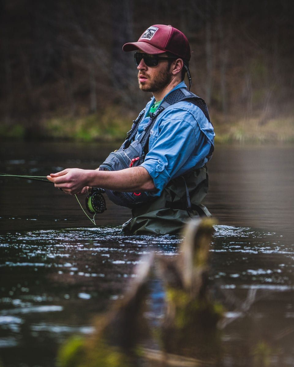 A man is fishing in a river with a fishing rod.