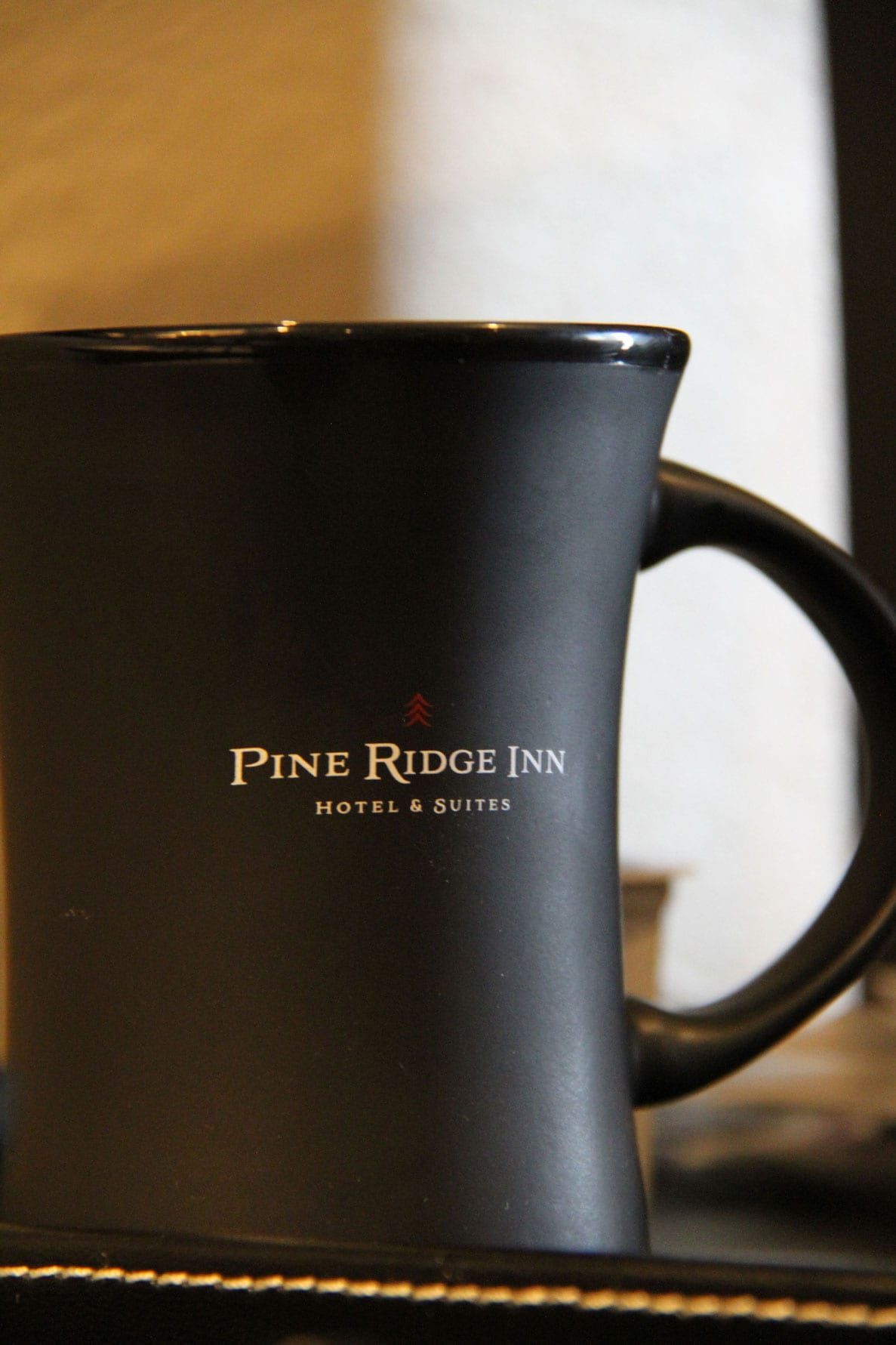 A black coffee mug that says pine ridge inn on it