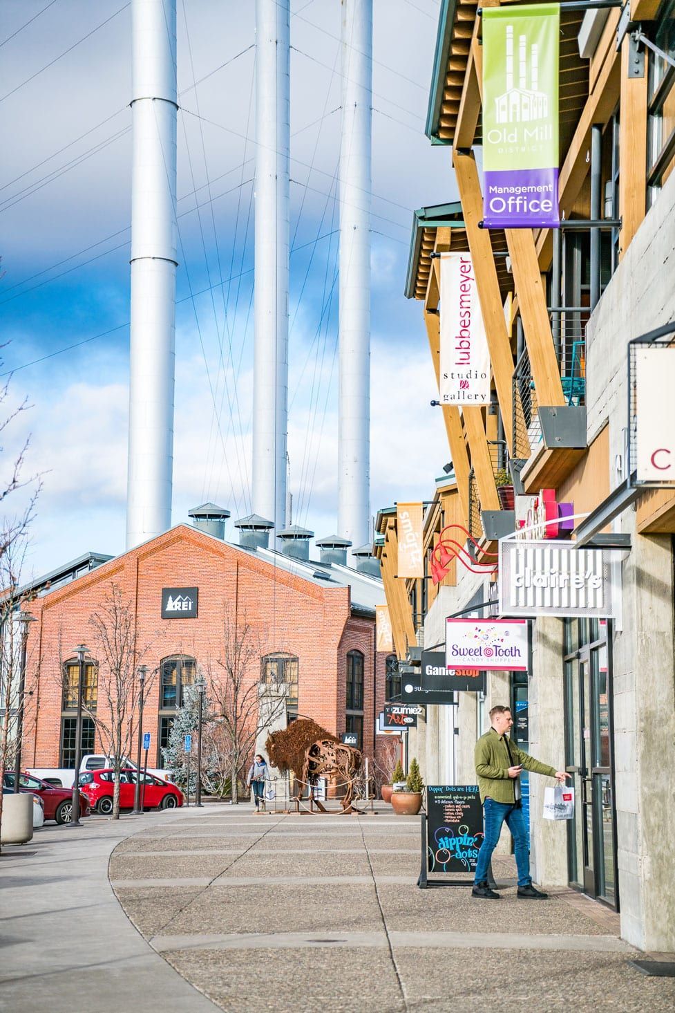 A man is standing on a sidewalk in front of a building.