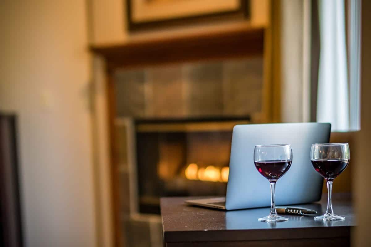 Two glasses of wine are sitting on a table next to a laptop.