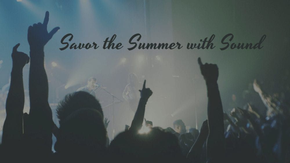 A crowd of people are raising their hands in the air at a concert.