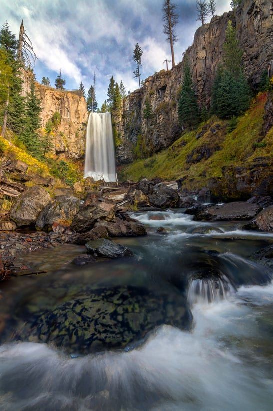 A waterfall is surrounded by rocks and trees in the middle of a river.