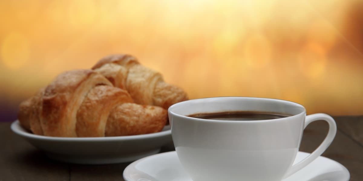 A cup of coffee and a plate of croissants on a table.