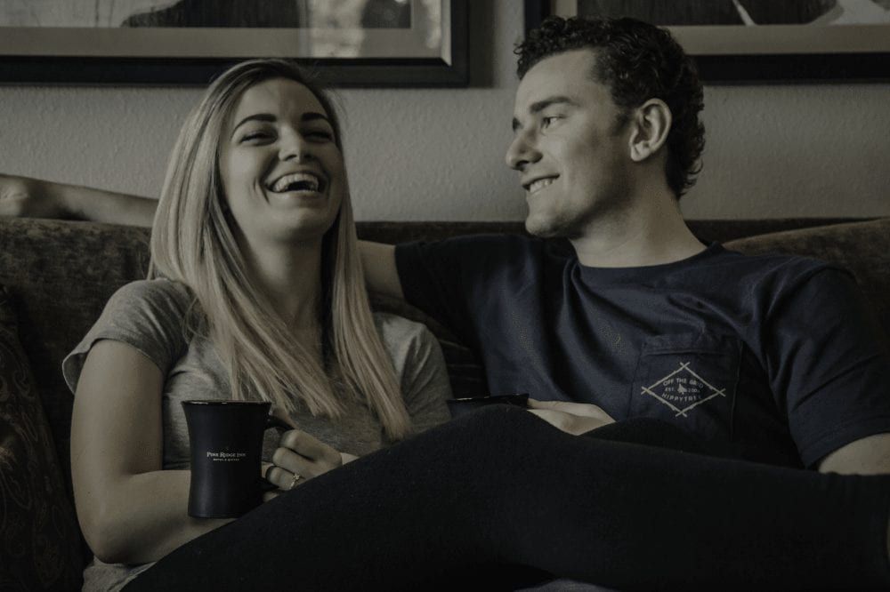 A man and a woman are sitting on a couch laughing.