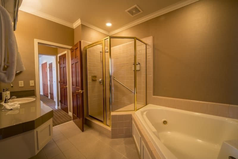 A bathroom with a tub , shower , sink and mirror.