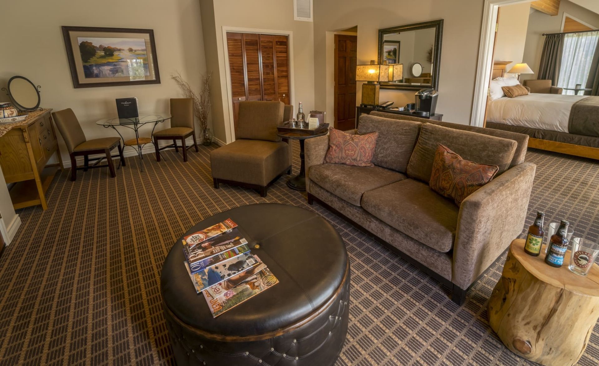 A living room with a couch , chairs , ottoman and a table.