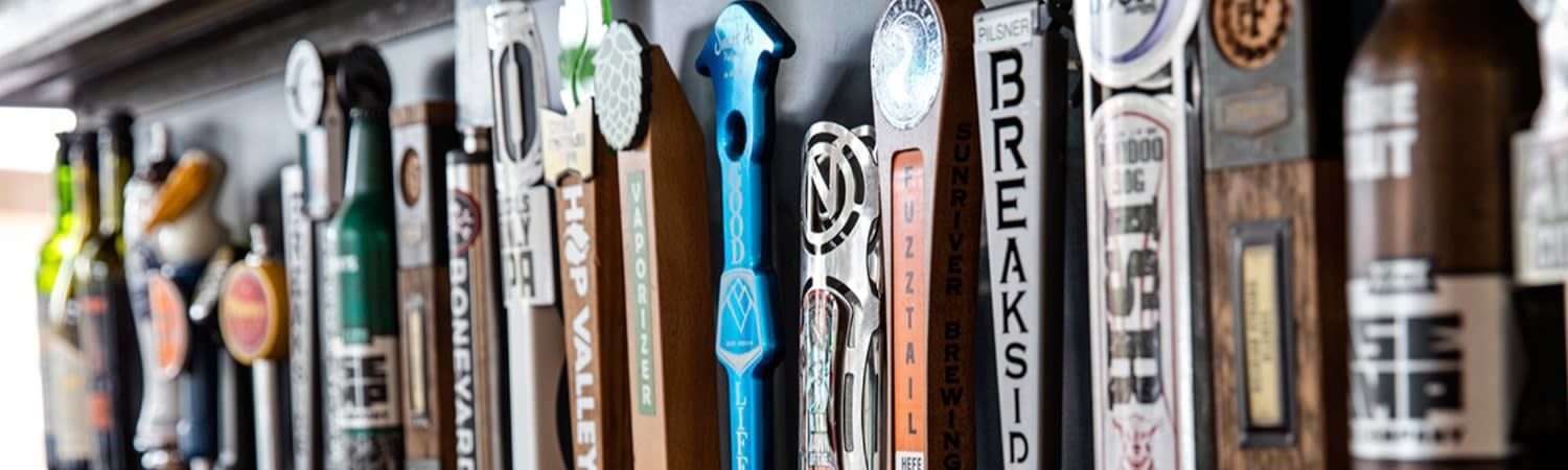 A row of beer taps hanging on a wall.