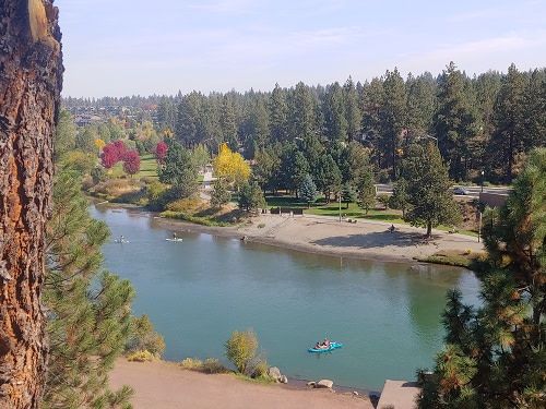 A lake surrounded by trees with a person in a kayak in the water.