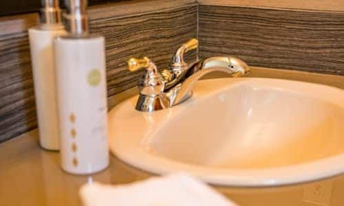 A bathroom sink with two bottles of lotion next to it.