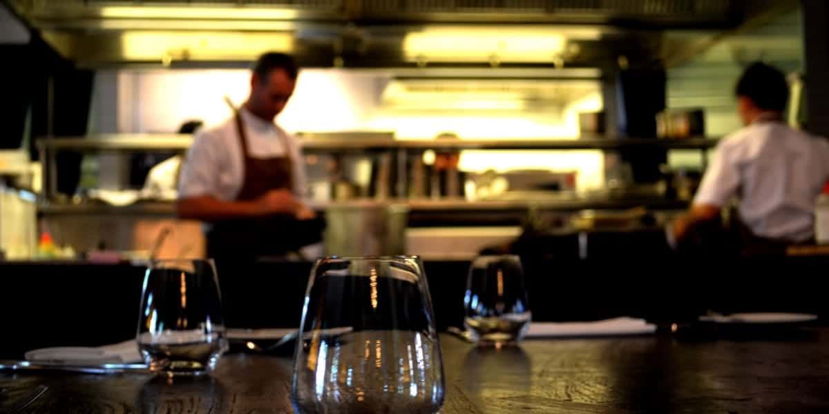 A blurry picture of a restaurant kitchen with a chef in the background.