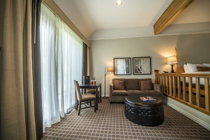 A hotel room with a couch , desk and chairs