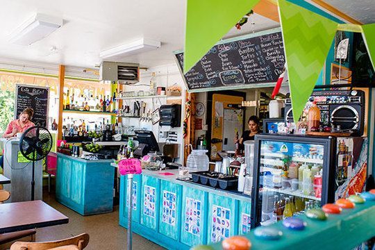The inside of a restaurant with tables and chairs and a counter.