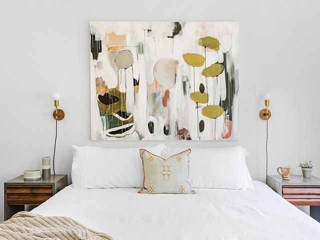 There is a painting on the wall above the bed.