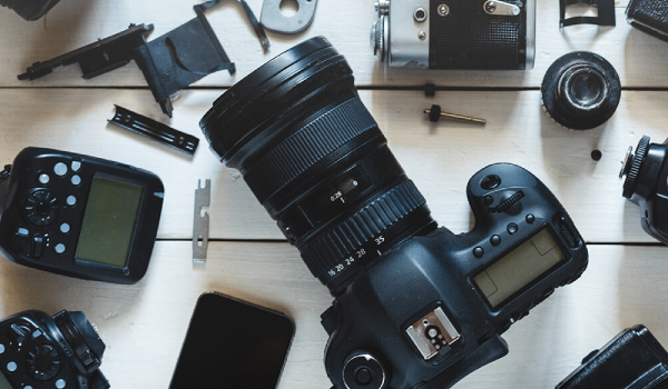 A camera is sitting on top of a wooden table surrounded by camera parts.