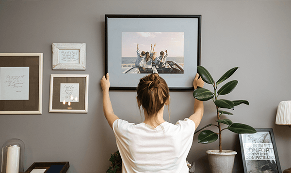 A woman is hanging a picture on a wall.