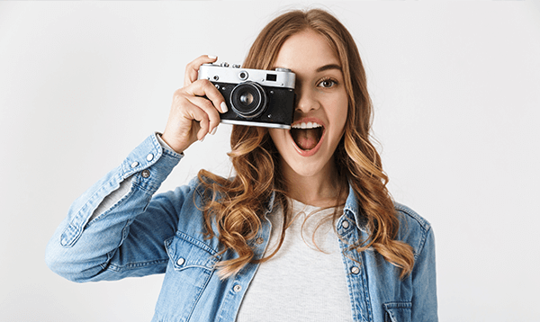 A woman is holding a camera in front of her face.