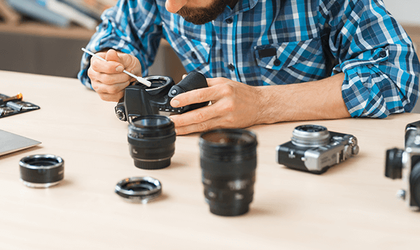 A man is repairing a camera with a screwdriver.