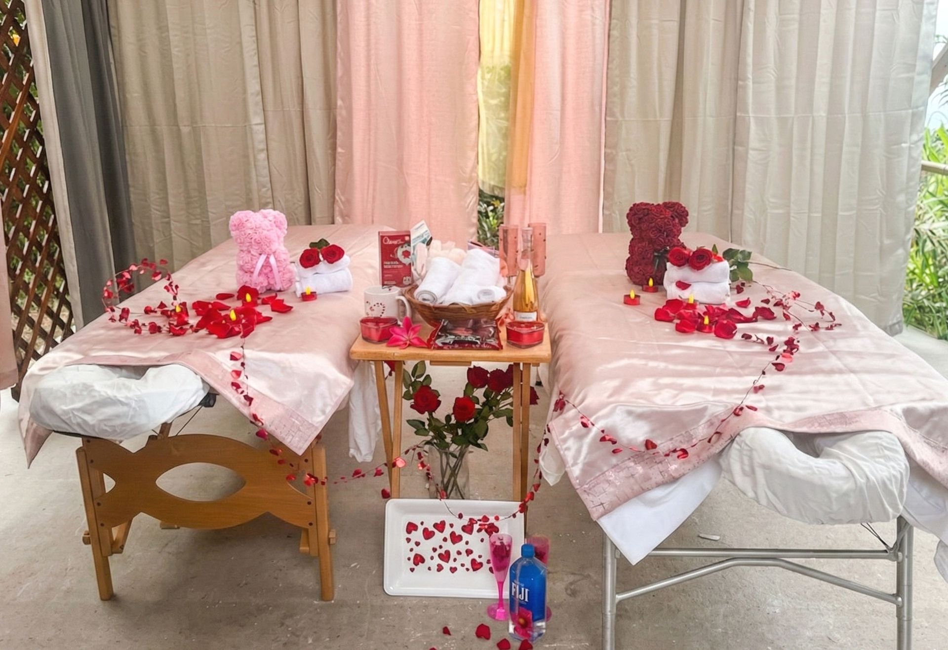 Two massage tables decorated with rose petals, flowers, and gifts, set for a couples massage.