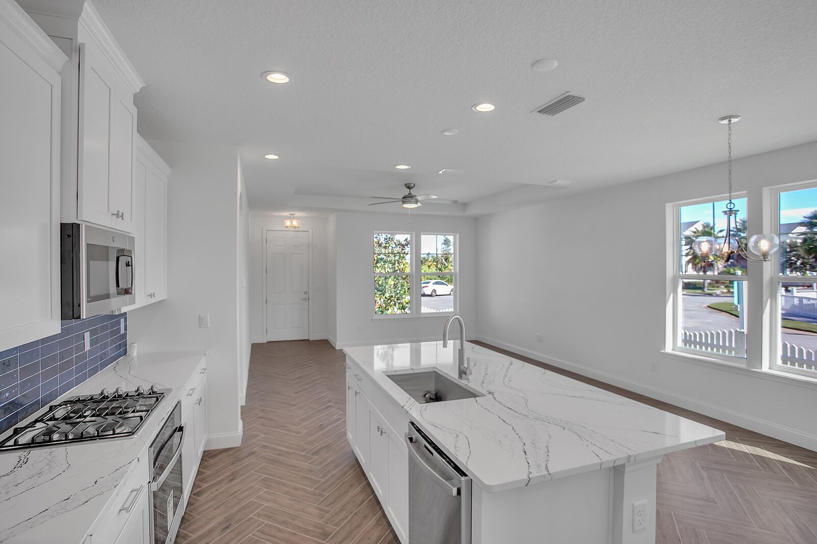 A kitchen with white cabinets , stainless steel appliances , and a large island.