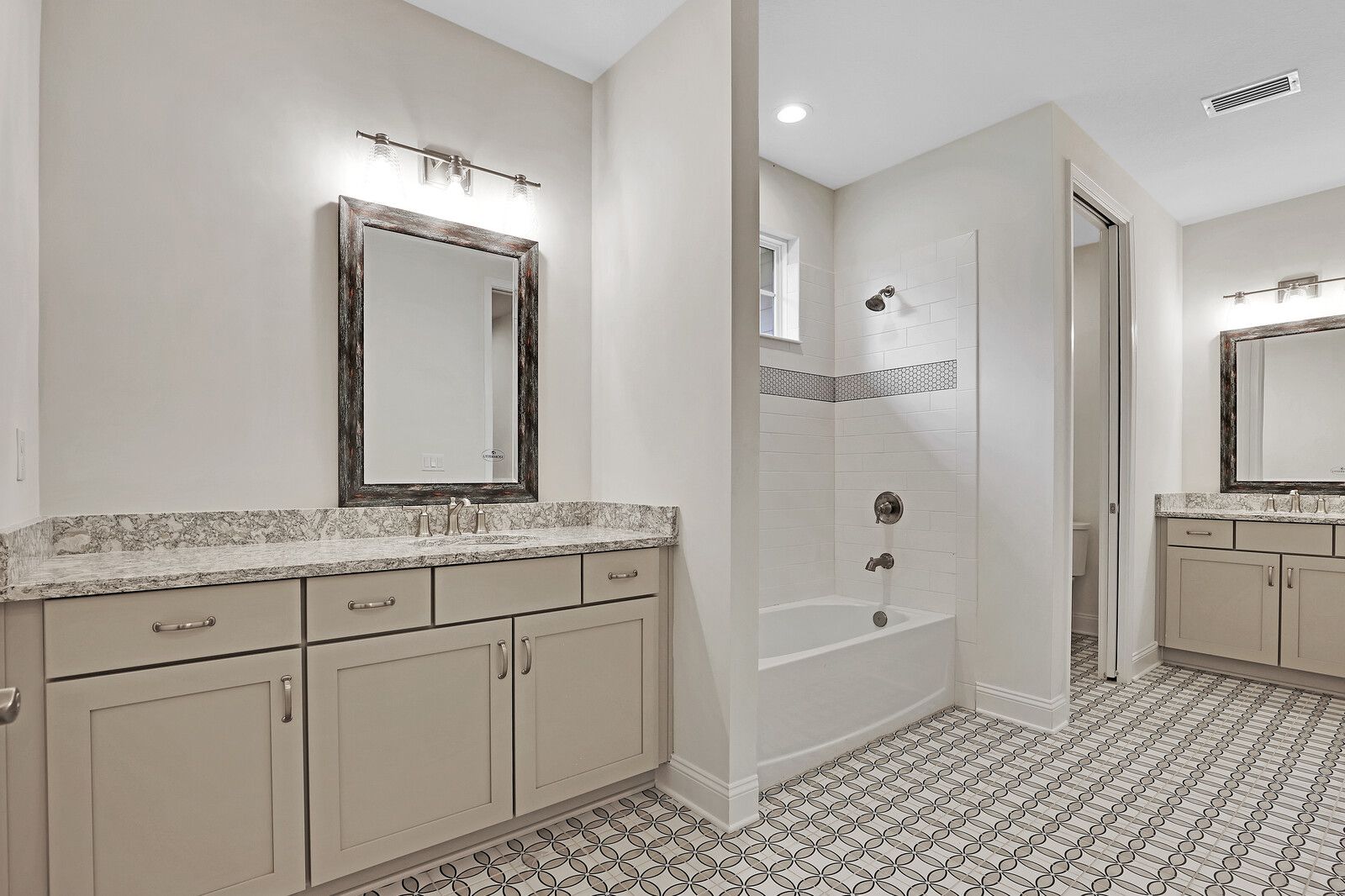 A bathroom with two sinks , a bathtub , and a mirror.