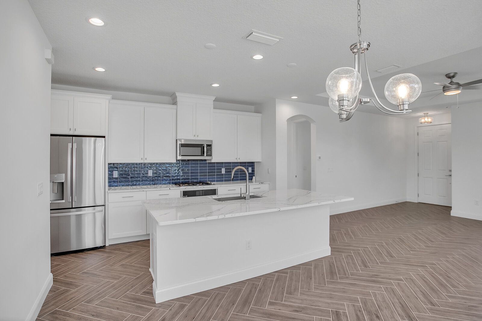 A kitchen with white cabinets , stainless steel appliances , and a large island.