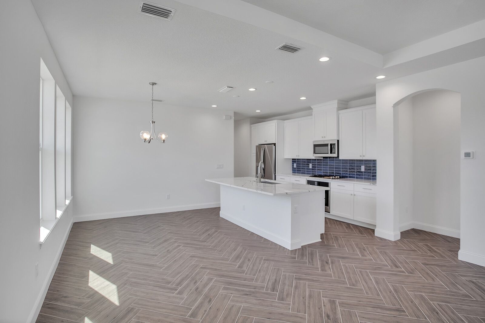 A large empty room with a kitchen and a large island in the middle.