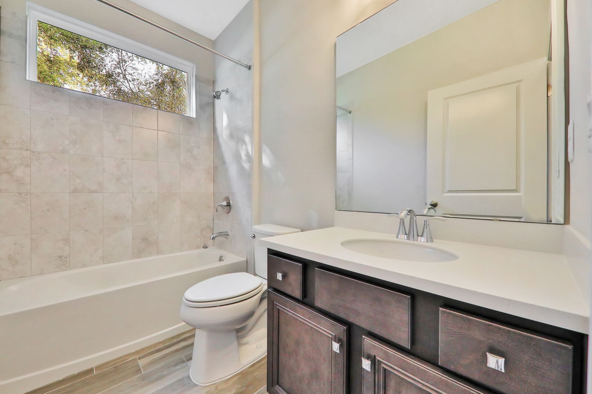 A bathroom with a toilet , sink , tub and mirror.