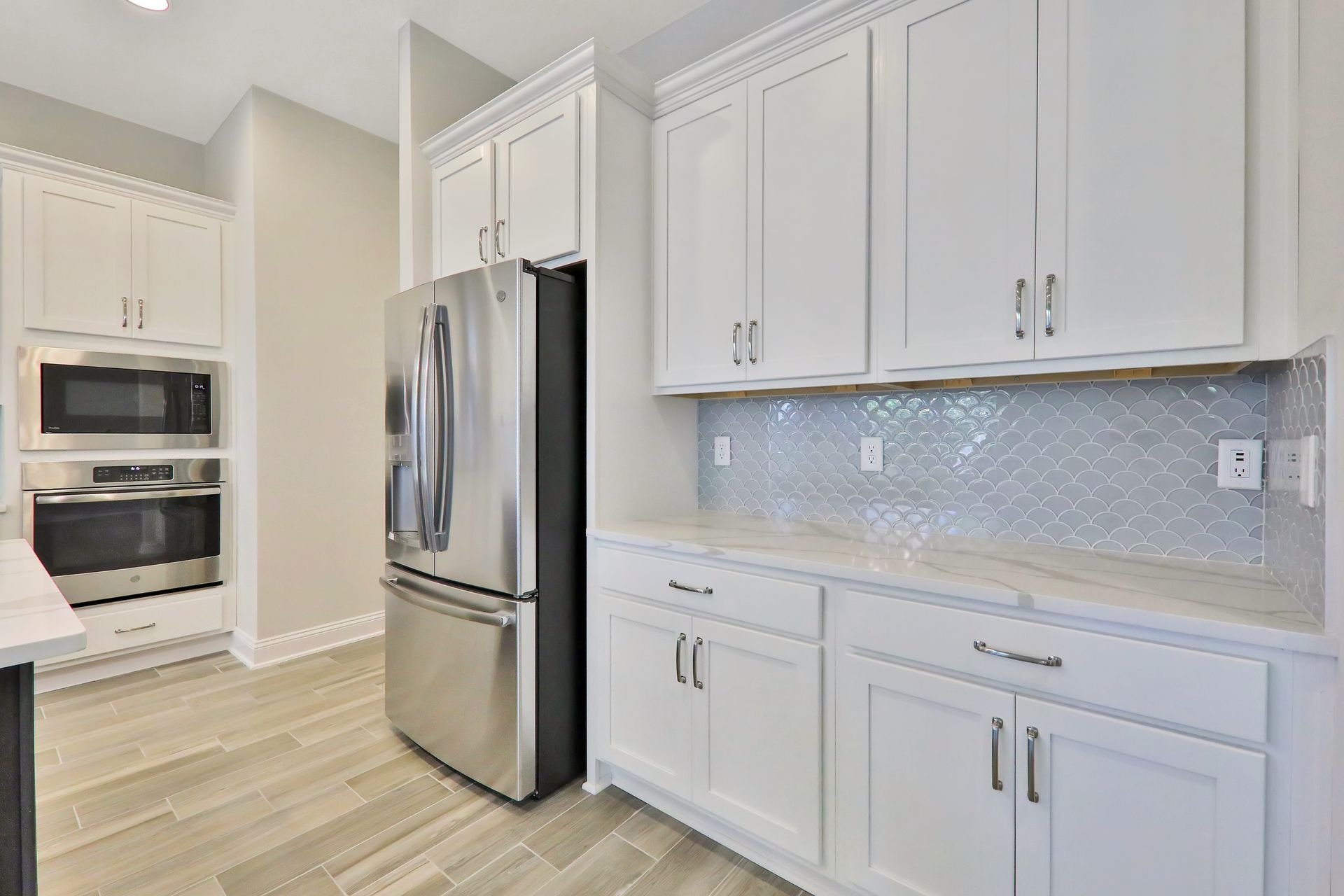 A kitchen with white cabinets , stainless steel appliances , a refrigerator and a microwave.
