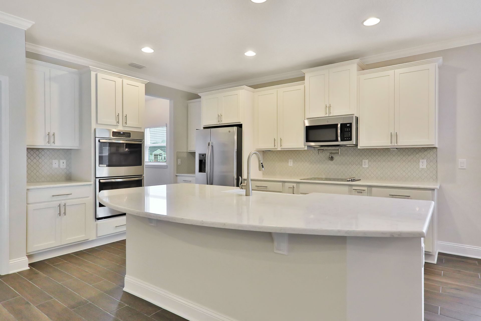 A kitchen with white cabinets , stainless steel appliances , and a large island.
