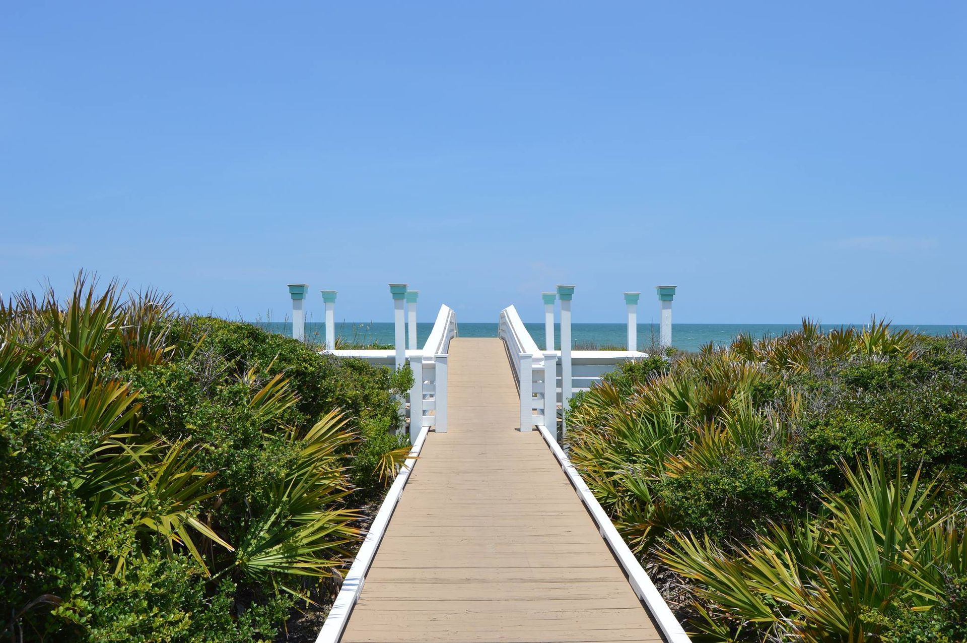A wooden walkway leading to the ocean on a sunny day