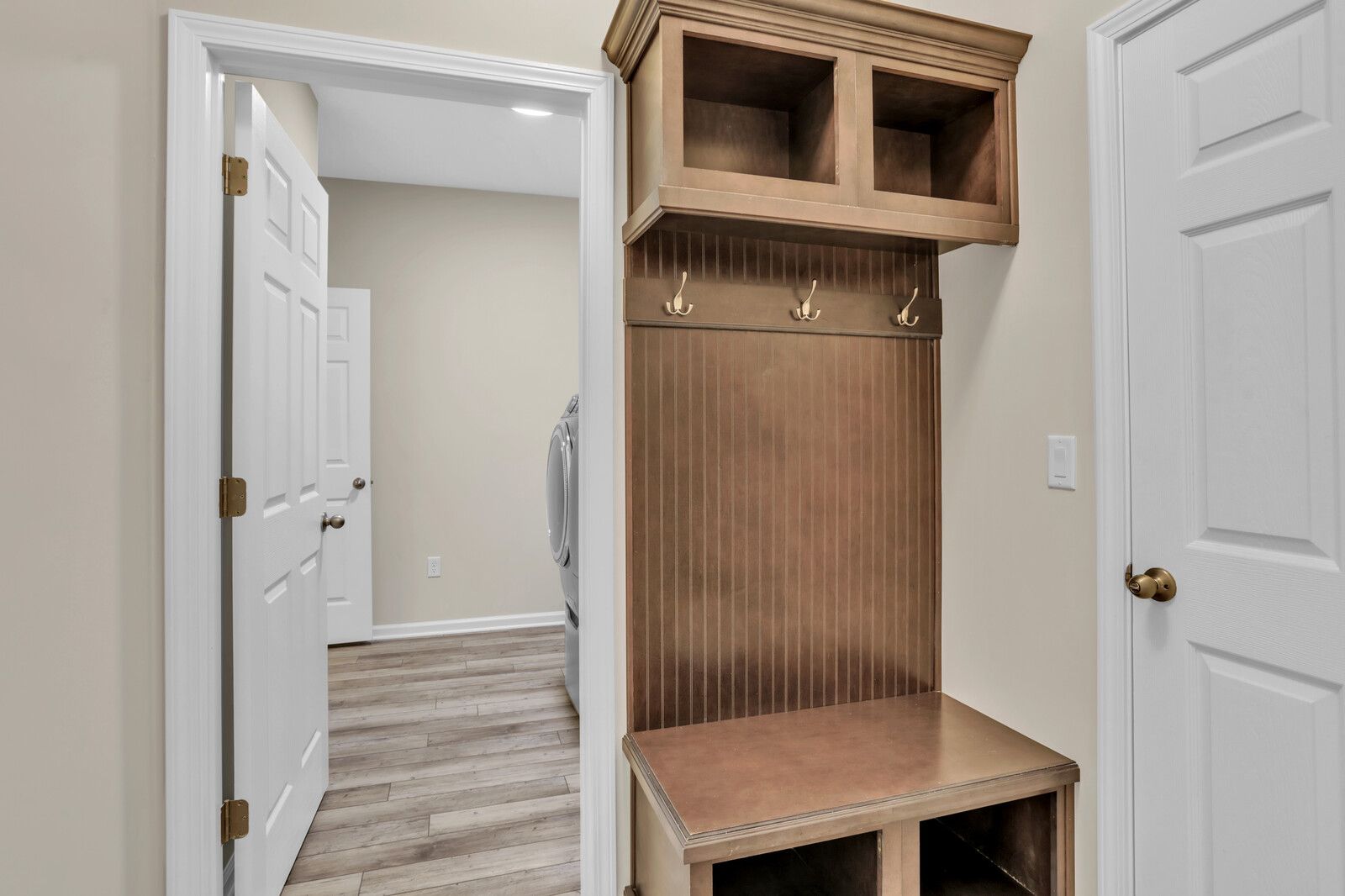 A mud room with a wooden bench and hooks on the wall.