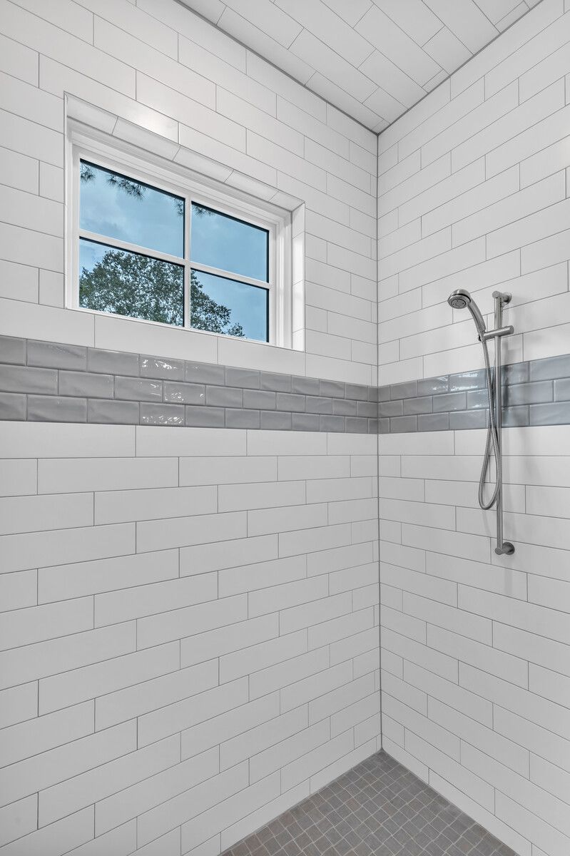 A shower with white tiles and a window.