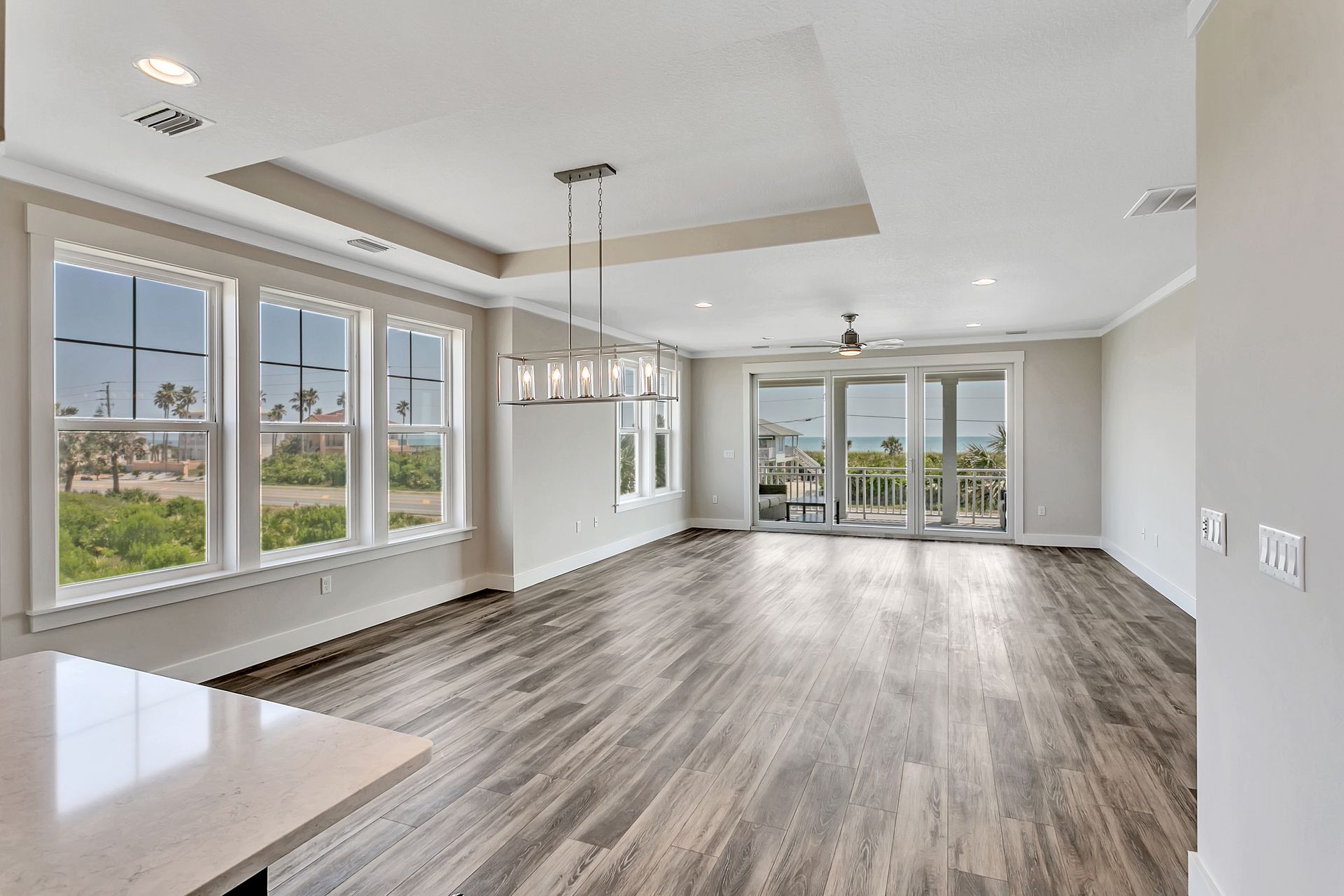 An empty living room with hardwood floors and lots of windows.