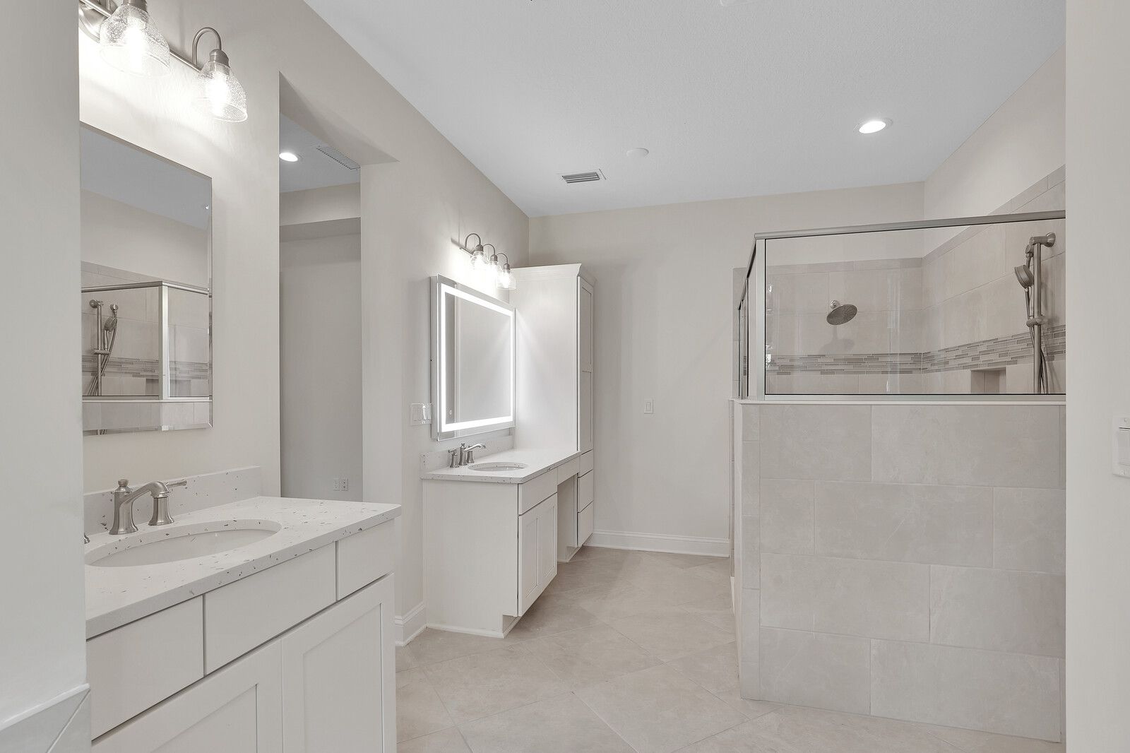 A bathroom with two sinks and a walk in shower.