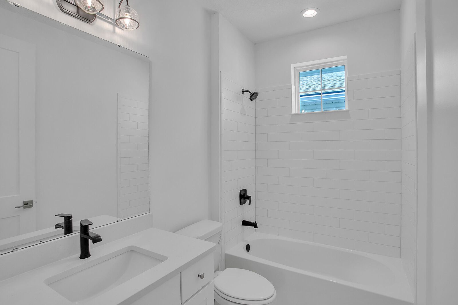 A bathroom with a sink , toilet , tub and mirror.