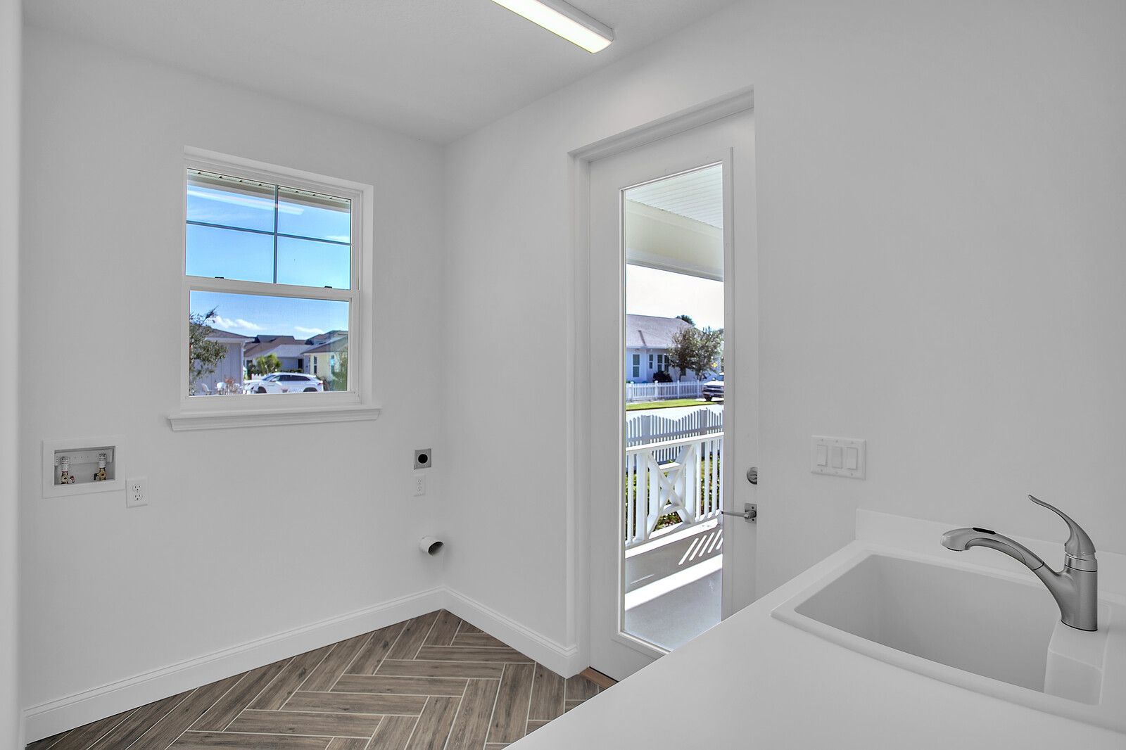 A laundry room with a sink and a window.