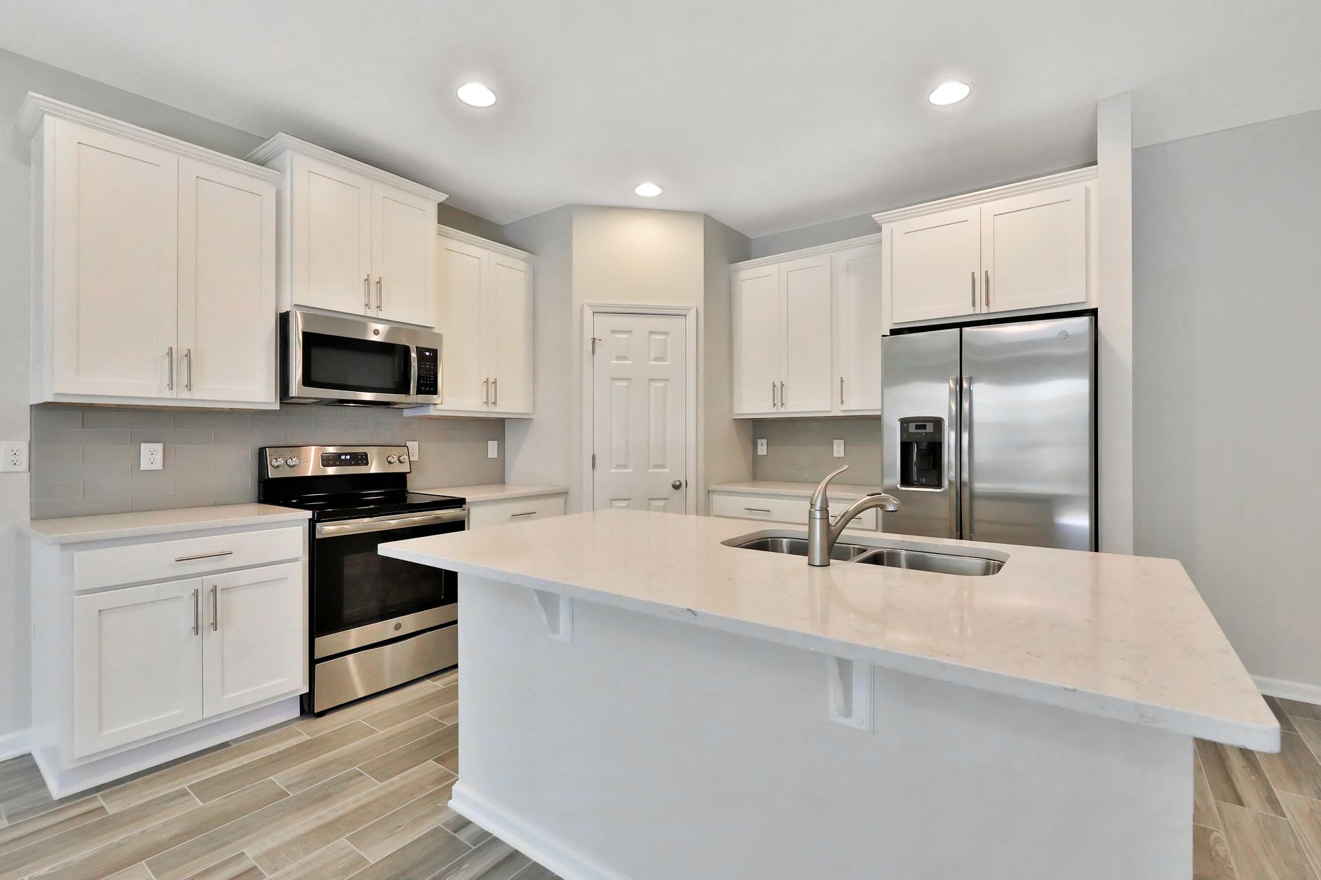 A kitchen with white cabinets , stainless steel appliances , and a large island.