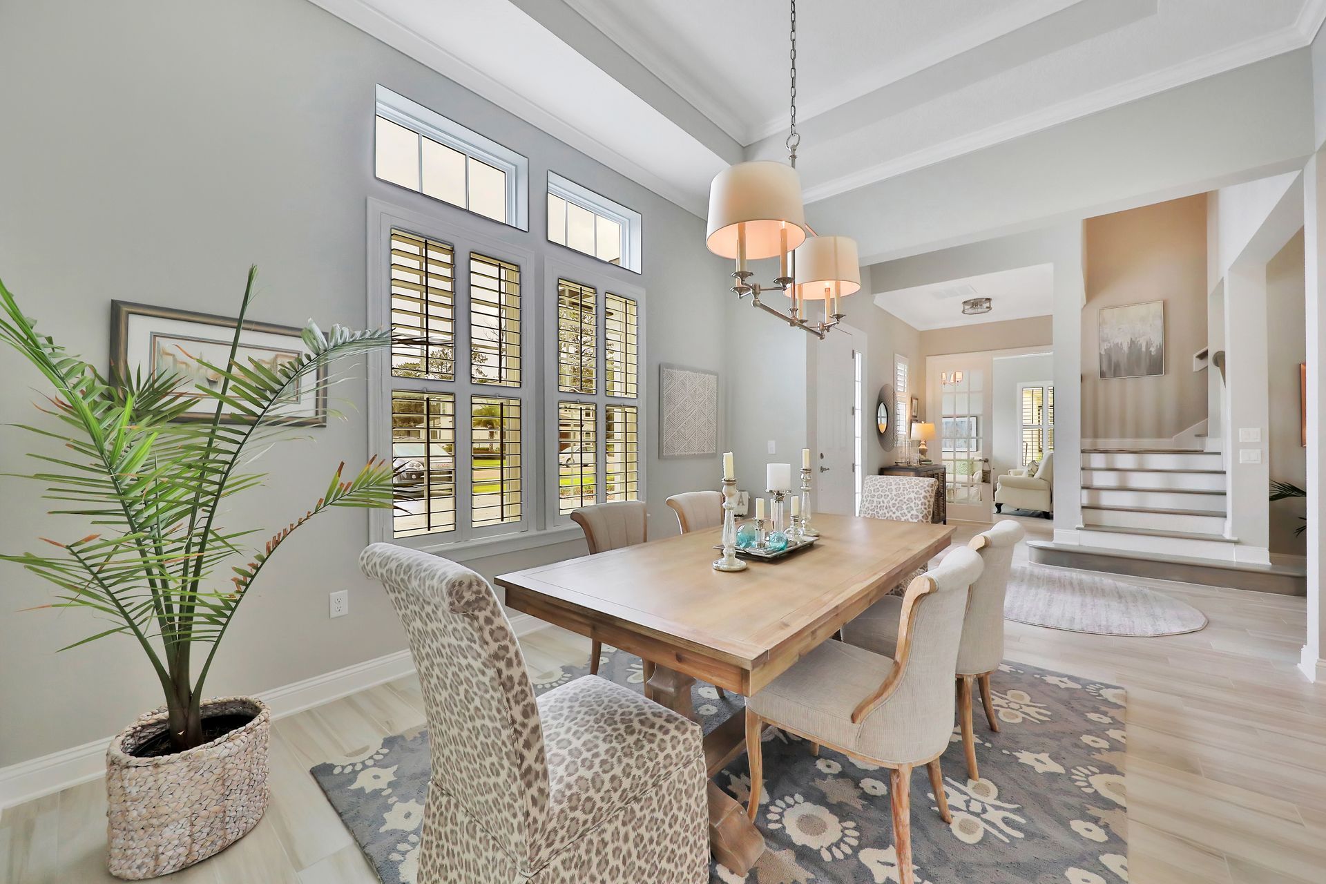 A dining room with a table and chairs and a potted plant.