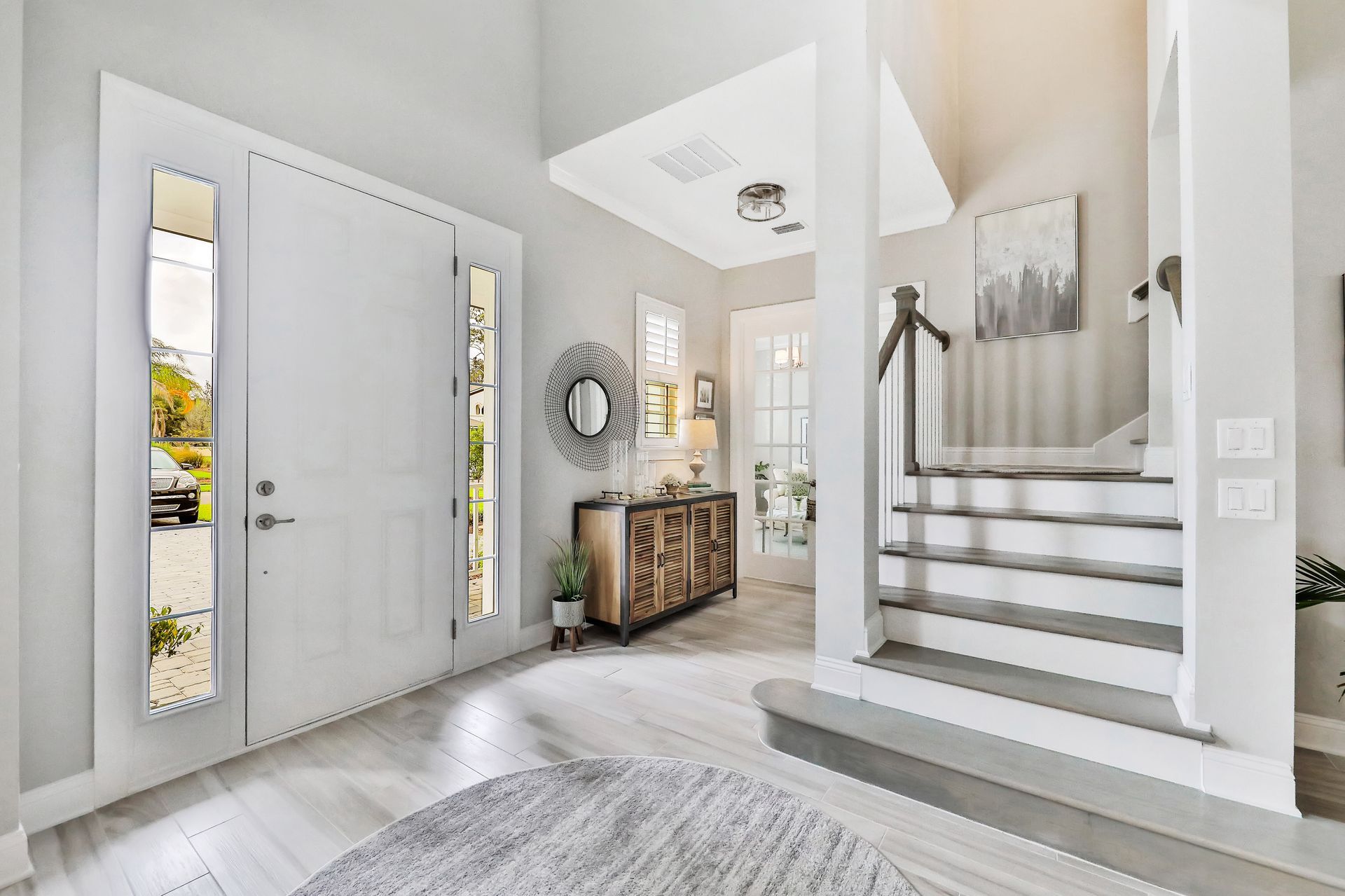 A hallway with a white door and stairs in a house.