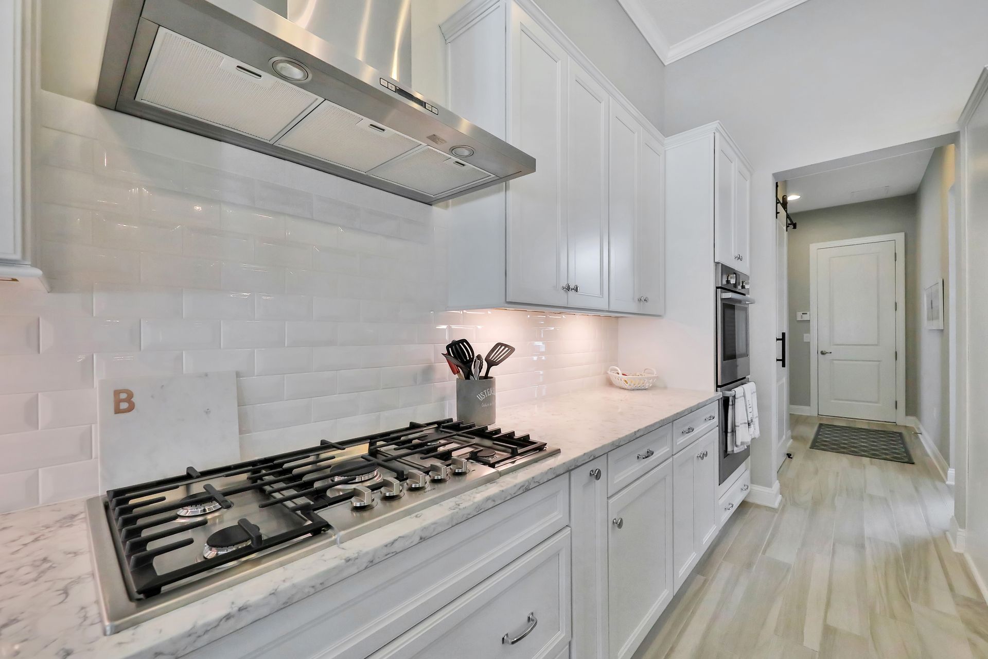A kitchen with white cabinets and a stove top oven.