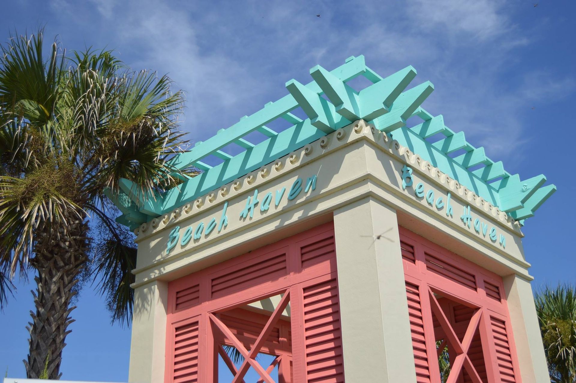 A pink and blue building with a palm tree in the background