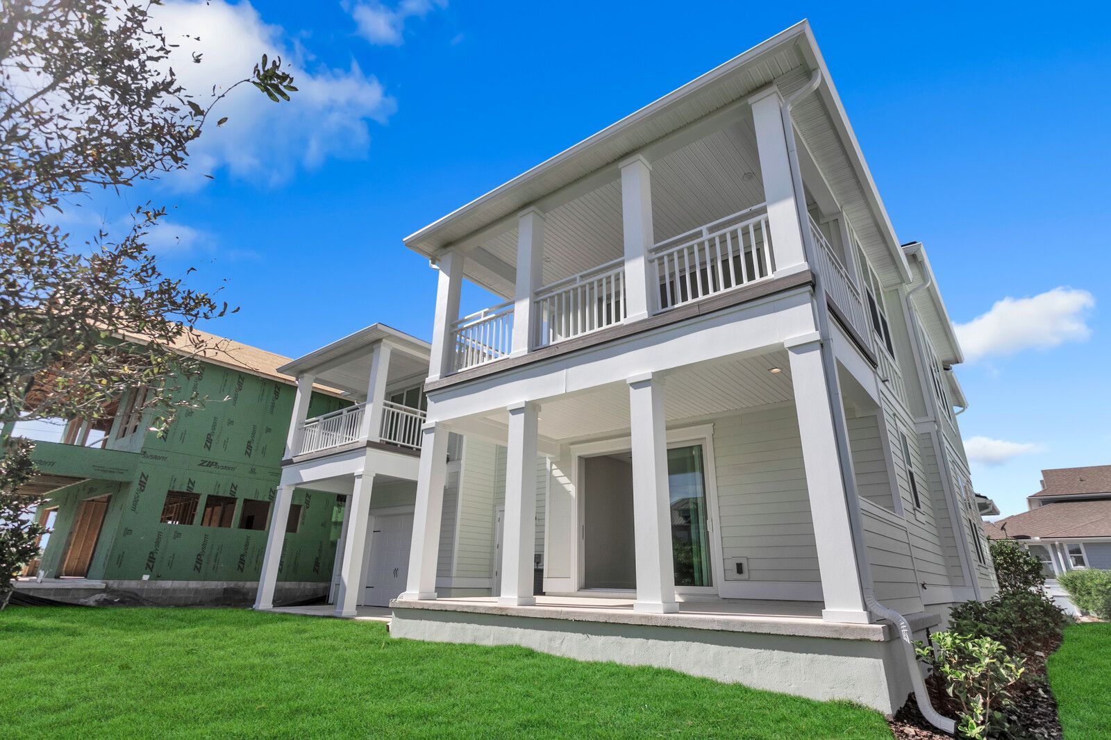 A large white house with a large porch is sitting on top of a lush green lawn.