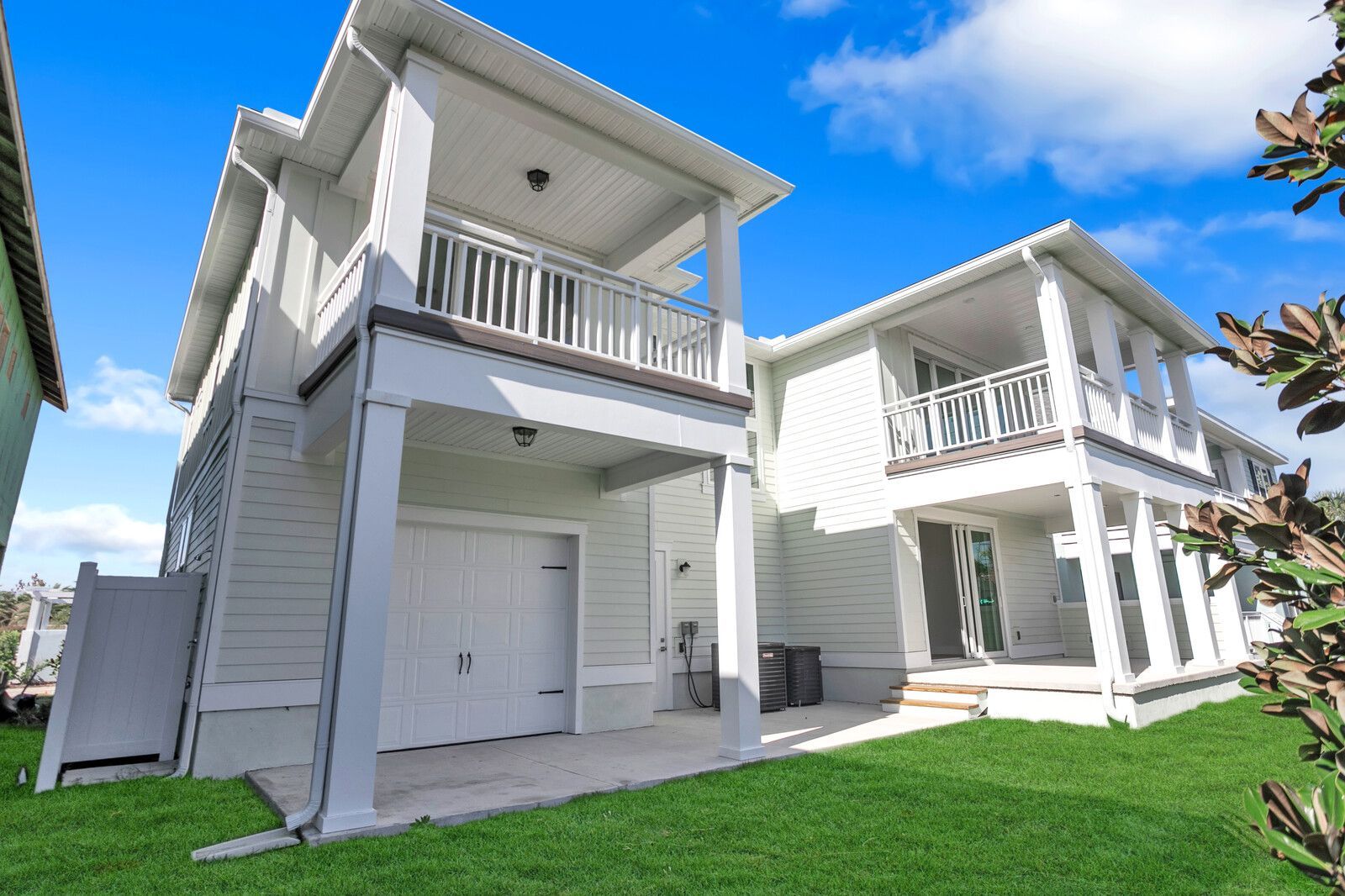 A white house with a lot of windows and balconies is sitting on top of a lush green lawn.