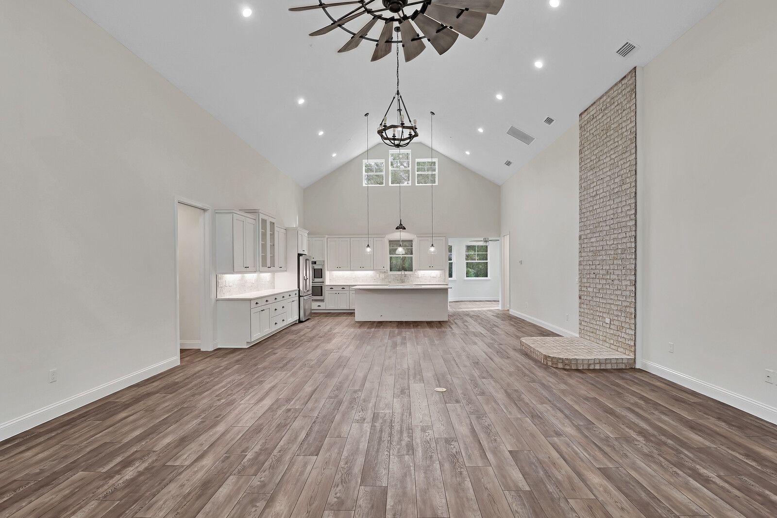 A large empty room with hardwood floors and a windmill hanging from the ceiling.