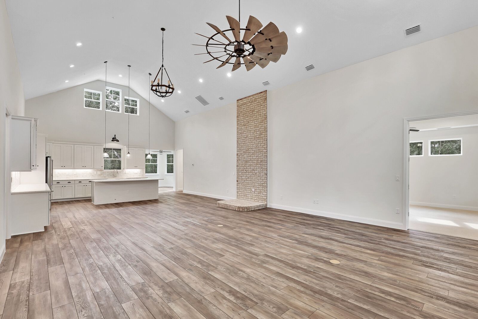 A large empty room with hardwood floors and a ceiling fan.