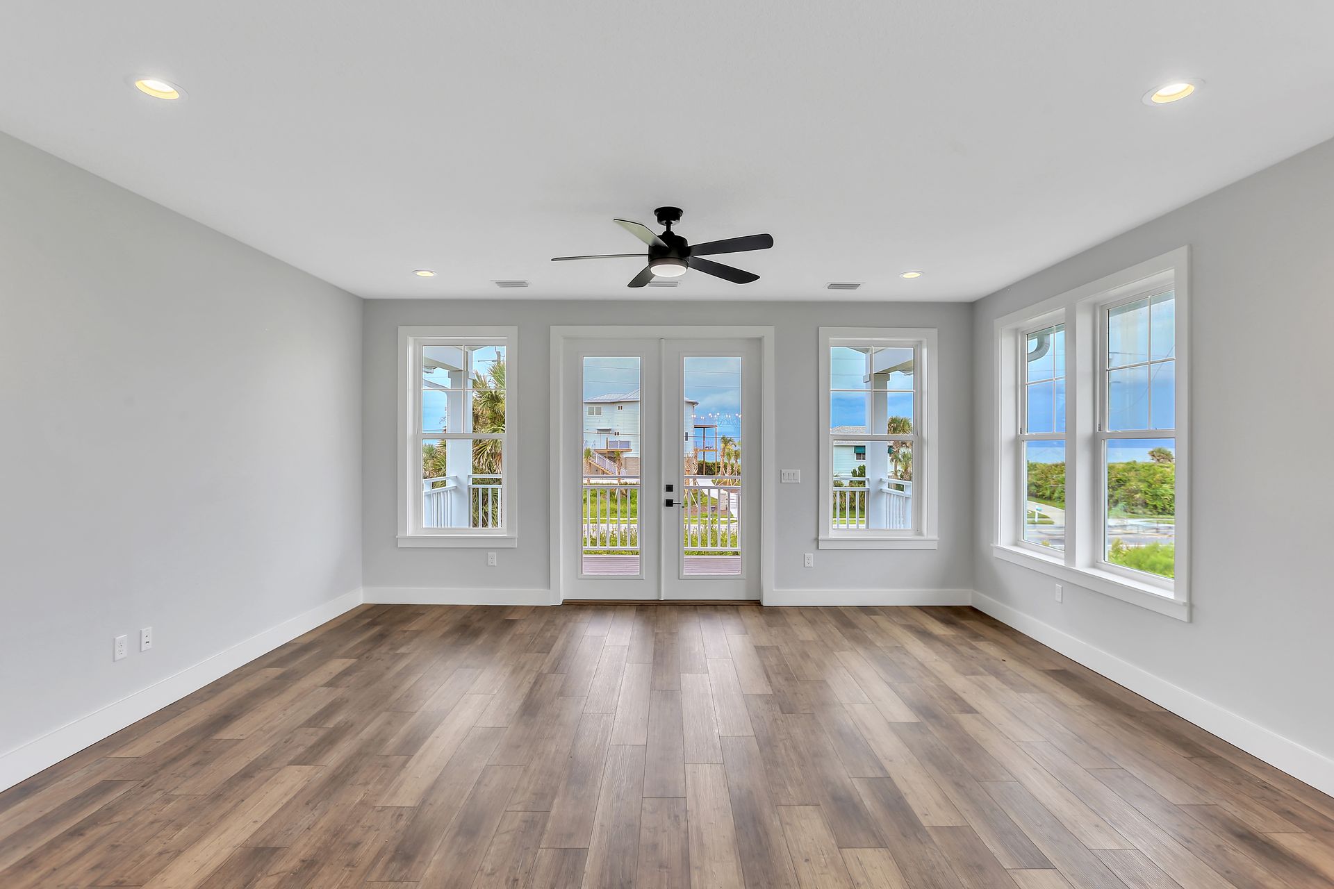 An empty living room with hardwood floors and a ceiling fan.