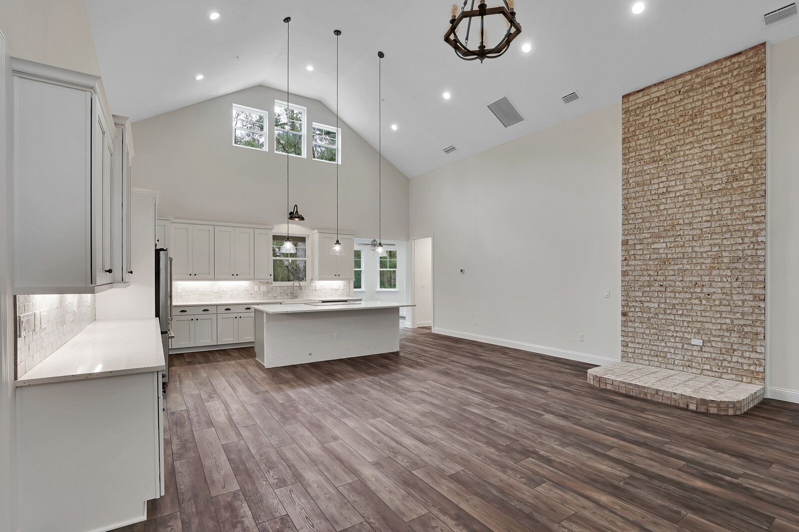 A kitchen and living room in a house with hardwood floors and white cabinets.