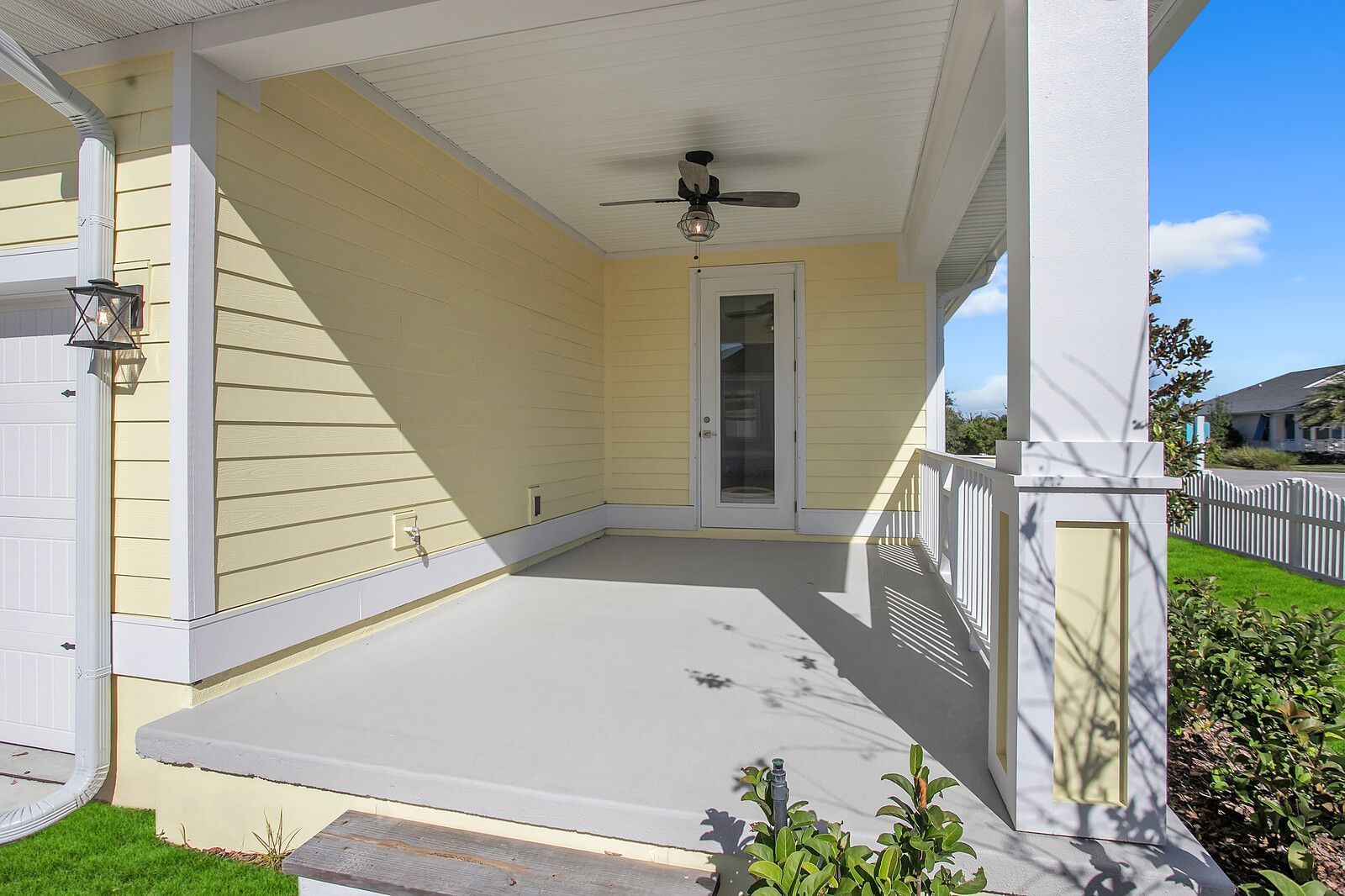 A yellow house with a porch and a ceiling fan