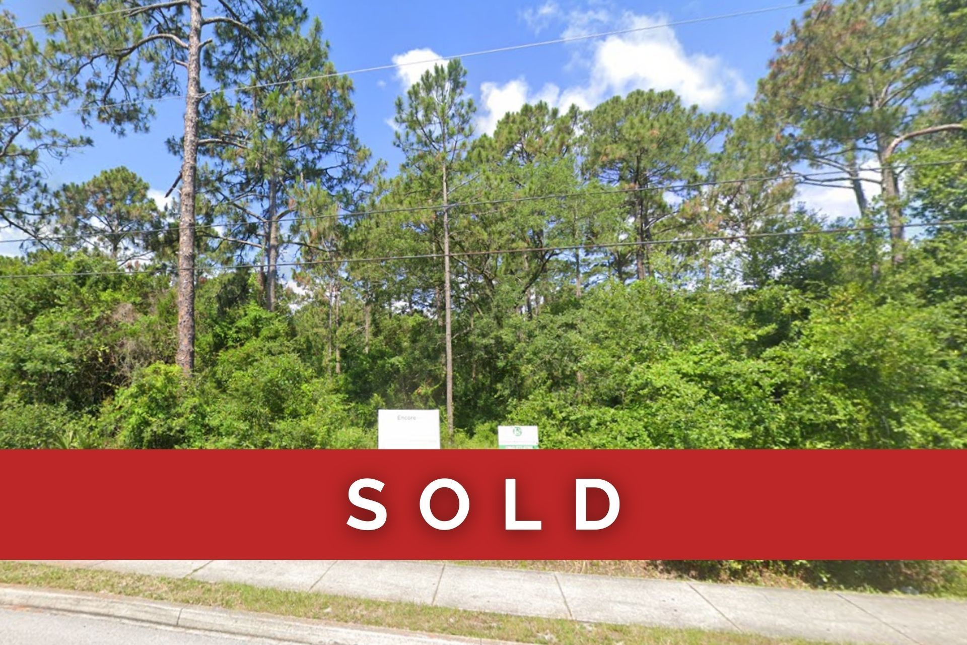 A lot with trees and a sign on the side of the road.