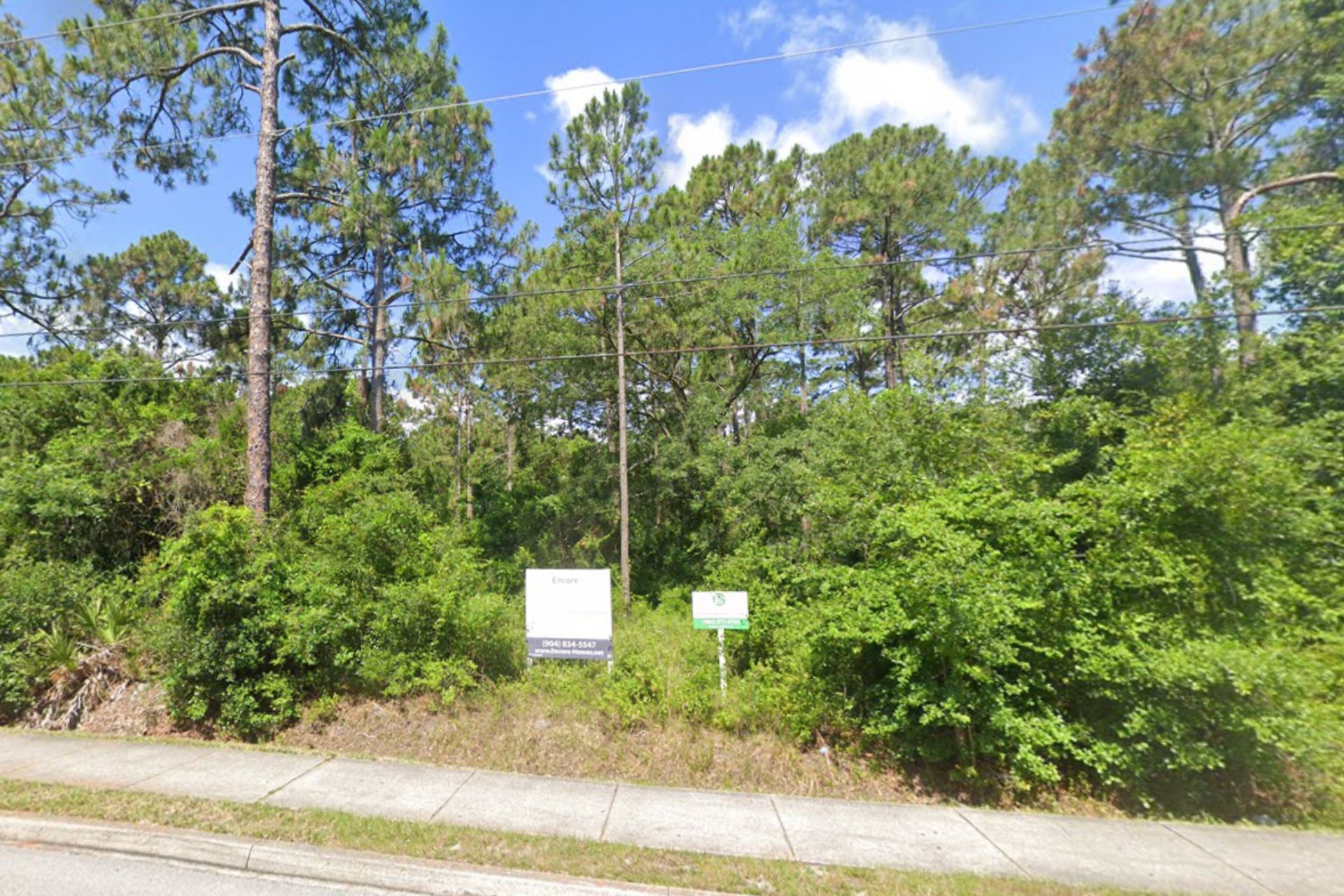 A lot with trees and a sign on the side of the road.